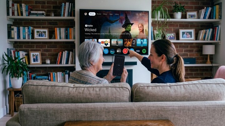 Older woman using an Android phone as a Samsung TV remote with a younger relative